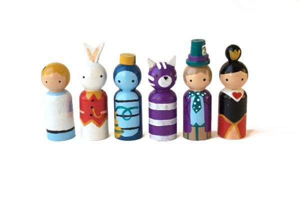 Alice in wonderland wooden figures standing in a row. 1 alice, 1 white rabbit, 1 caterpillar, 1 cheshire cat, 1 mad hatter, 1 queen of hearts