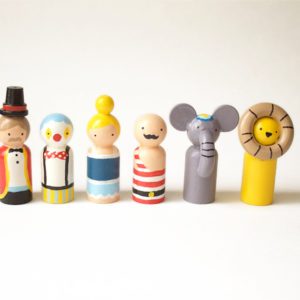 6 small wooden circus toys standing in a row. 1 ringmaster, 1 clown, 1 trapeze girl, 1 strongman, 1 elephant, and 1 lion