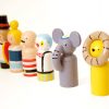 side view of 6 small wooden circus toys standing in a row. 1 ringmaster, 1 clown, 1 trapeze girl, 1 strongman, 1 elephant, and 1 lion