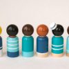 back view of 6 wooden sailor toy figurines standing in a row. 1 pale skinned boy with blond curly hair and a hat, 1 pale skinned boy with brown hair, 1 medium skinned boy with black hair, 1 medium skinned girl with brown pigtails, 1 pale skinned girl with black hair, 1 pale skinned girl with red hair.