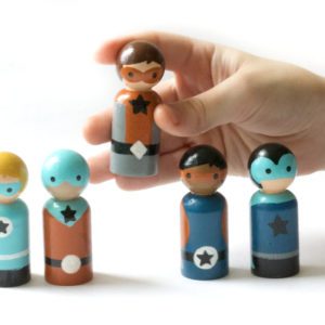 5 superhero gifts for kids. 4 superhero boy peg dolls standing and one being held by a child’s hand. 1 play skinned boy with blond hair, 1 medium skinned boy with a mask, 1 pale skinned boy with brown hair, 1 dark skinned boy with black hair, 1 pain skinned boy with a mask.