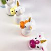 top view of 5 miniature rainbow unicorn toys standing in a row. 1 red unicorn, 1 orange unicorn, 1 yellow unicorn, 1 green unicorn, 1 blue unicorn.