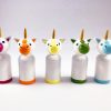 5 miniature rainbow unicorn toys standing in a row. 1 red unicorn, 1 orange unicorn, 1 yellow unicorn, 1 green unicorn, 1 blue unicorn.