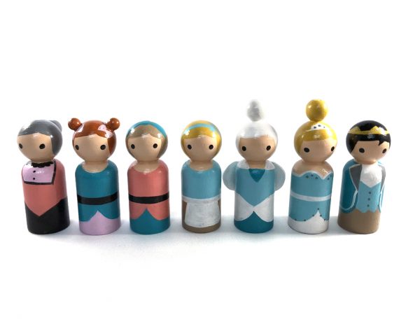 7 Cinderella wooden toy dolls standing in a row. 1 evil stepmother, 2 evil stepsisters, 1 cinderella in rags, 1 fairy godmother, 1 cinderella in fancy dress, 1 prince.