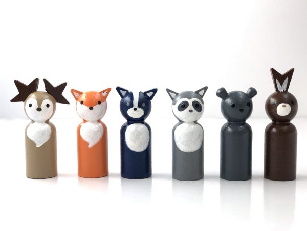 6 woodland animal toy figurines standing in a row. 1 deer, 1 fox, 1 skunk, 1 raccoon, 1 bear, and 1 rabbit
