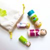 4 wooden family peg dolls laying down, coming out of a bag. 1 mother, 1 boy, 1 girl, and 1 dad
