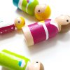 close up of 4 wooden family peg dolls laying down. 1 mother, 1 boy, 1 girl, and 1 dad