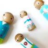close up of 4 wooden family toys laying down. 1 mother, 1 boy, 1 girl, and 1 dad