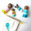 4 wooden peg dolls laying down, coming out of a bag. 1 mother, 1 boy, 1 girl, and 1 dad