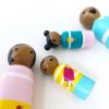 close up of 4 wooden peg dolls laying down. 1 mother, 1 boy, 1 girl, and 1 dad