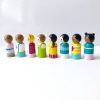 side view of Multicultural peg dolls set with 8 dolls standing in a row. 1 boy with medium skin and brown hair, 1 girl with medium skin and brown hair, 1 boy with pale skin and brown hair, 1 girl with pale skin and blond hair, 1 boy with pale skinned and black hair, 1 girl with pale skinned and black pig tails, 1 boy with dark skin and black hair, 1 girl with dark skinned and black hair buns.