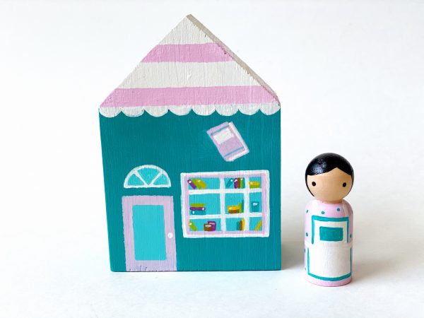 1 small wooden bookshop toy and one store clerk standing.