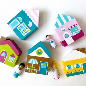 5 wooden toy block houses and 3 peg dolls laying down. 1 bookstore with worker, 1 cafe with worker, 1 bakery with worker, 1 yellow house and 1 green house.