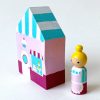 Side view of 1 wooden bakery block toy and one female bakery worker standing.