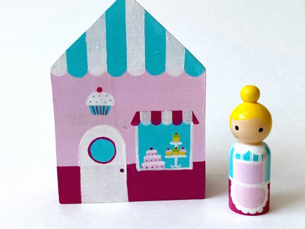 1 wooden bakery block toy and one female bakery worker standing.