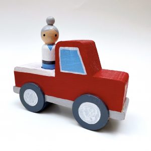 red vintage wood truck toy with peg doll riding in the back