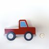 side view of red vintage wood truck toy with quarter for size