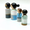 side view of 4 old style wooden toys standing in a row. 1 medium skinned man with black hair, 1 pale skinned woman with black hair, 1 pale skinned boy with brown hair, 1 dark skinned girl with black hair.